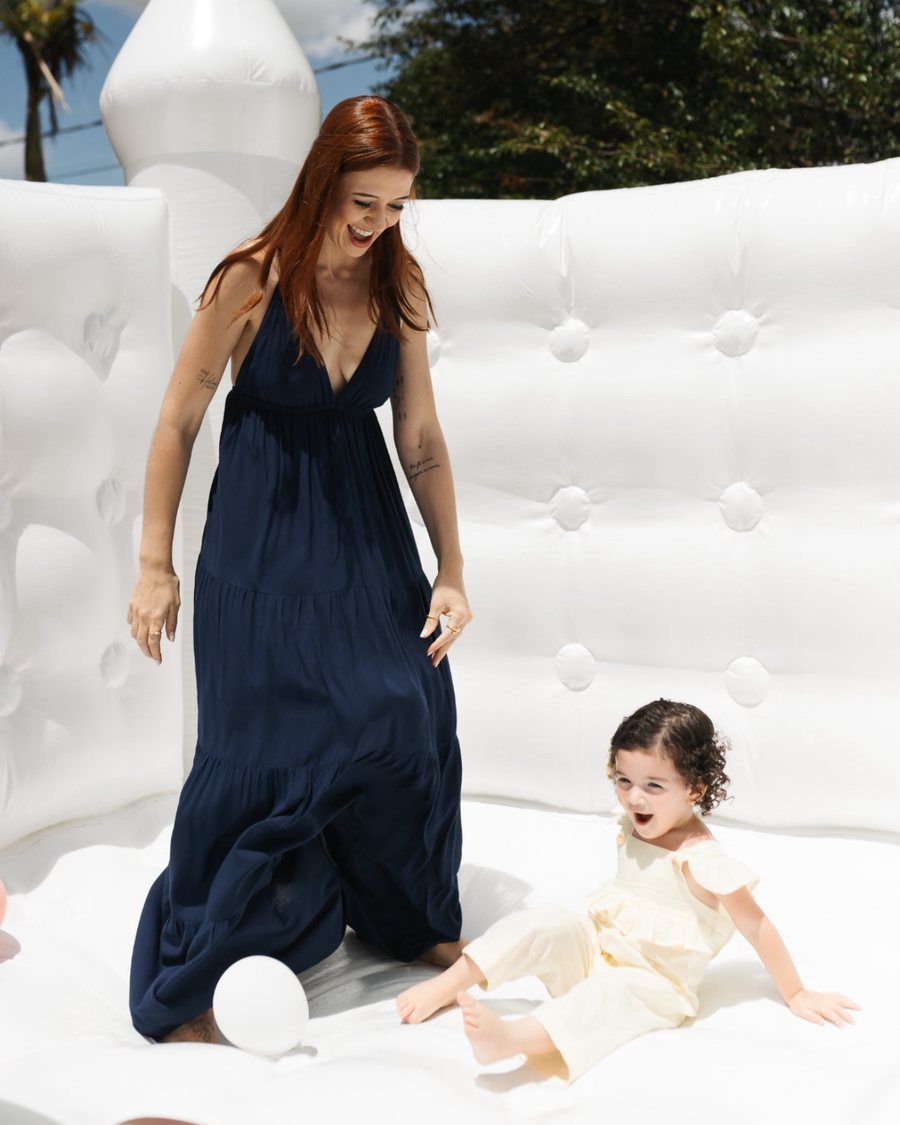 Mãe e filha brincando dentro do castelinho inflável branco